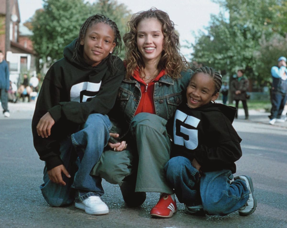 Jessica Alba as Honey Daniels crouches with Zachary Isaiah Williams (Raymond) and Romeo Miller (Benny, credited as Lil’ Romeo), sporting casual Y2K streetwear with bright red Adidas sneakers that spotlight her character’s urban dance style
