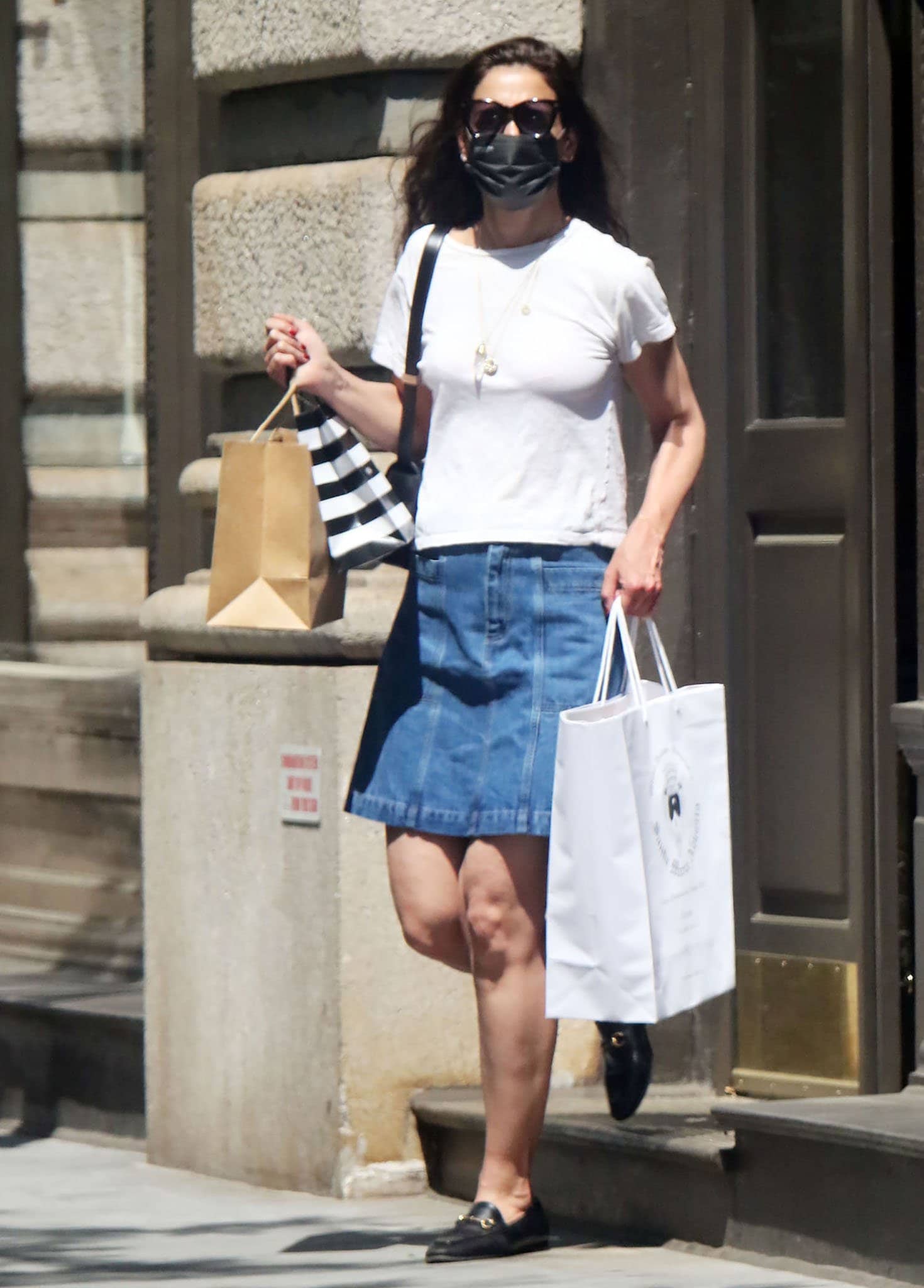 To replicate Katie Holmes’ effortlessly chic off-duty look, pair a classic white tee with an A-line denim mini skirt, add timeless Gucci Jordaan loafers, layer delicate gold jewelry, and finish with oversized sunglasses for a touch of sophistication