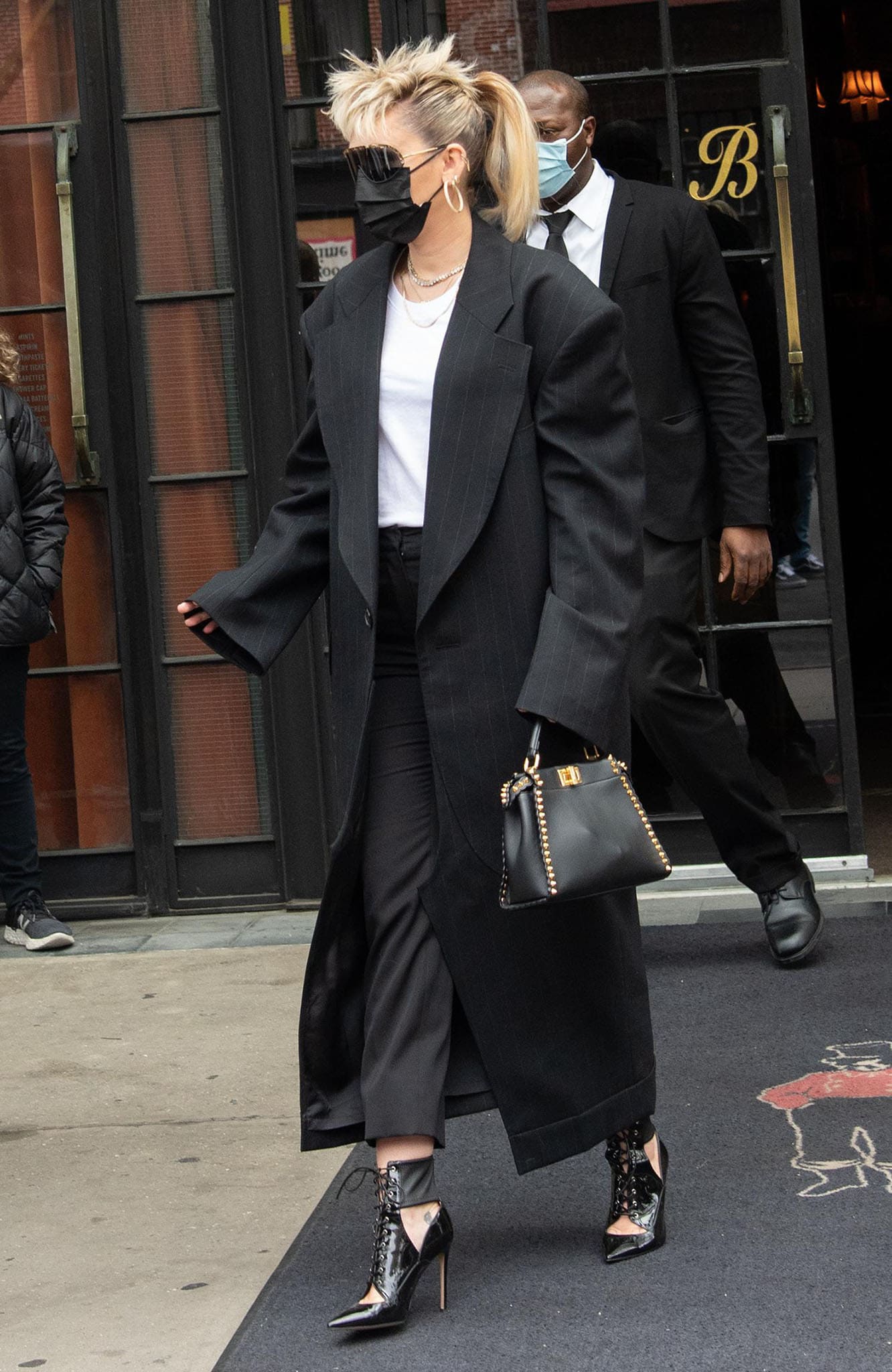 Miley Cyrus wears Junya Watanabe pinstriped long coat over a white tee and black pants combo