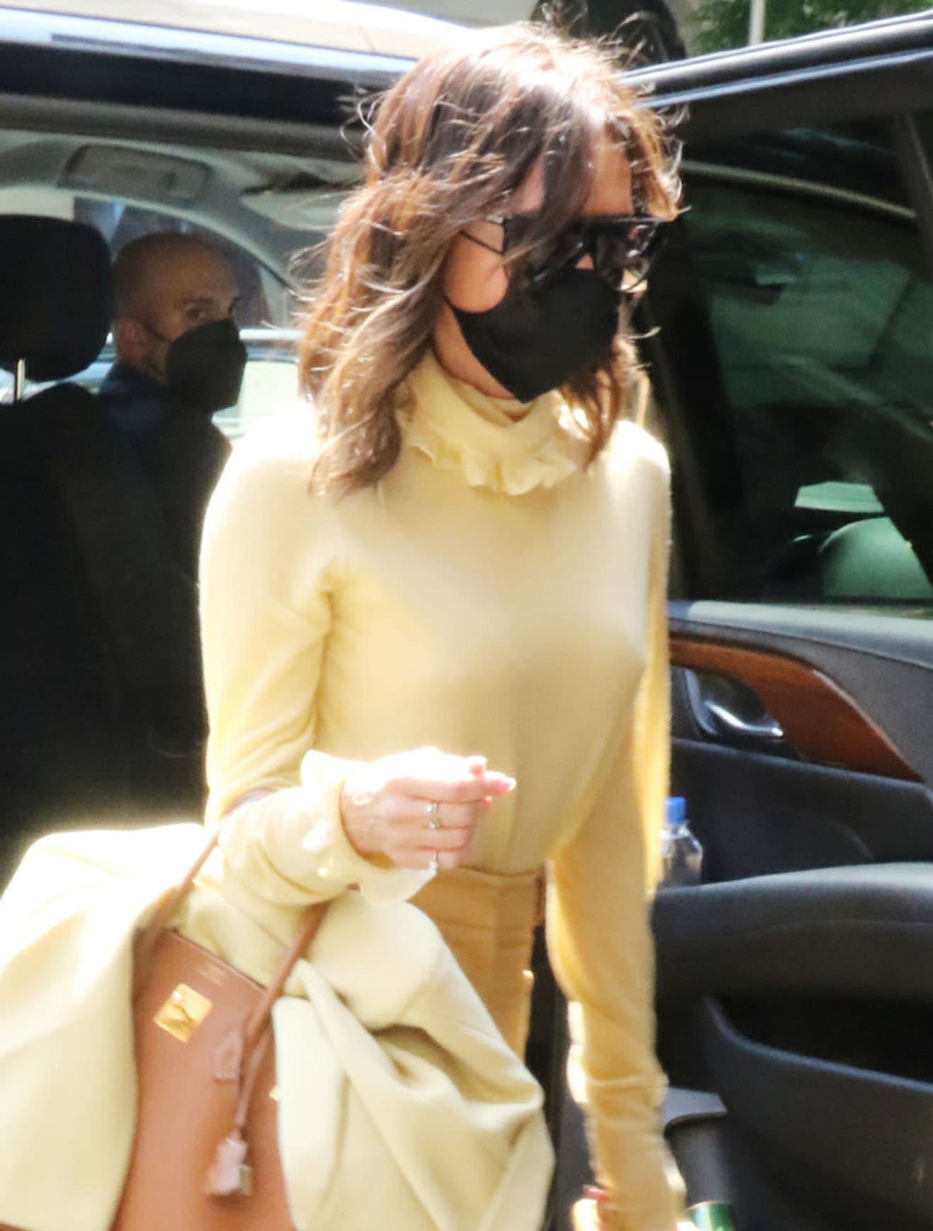 Victoria Beckham styles her hair in curls and keeps a low profile with retro sunnies and a face mask