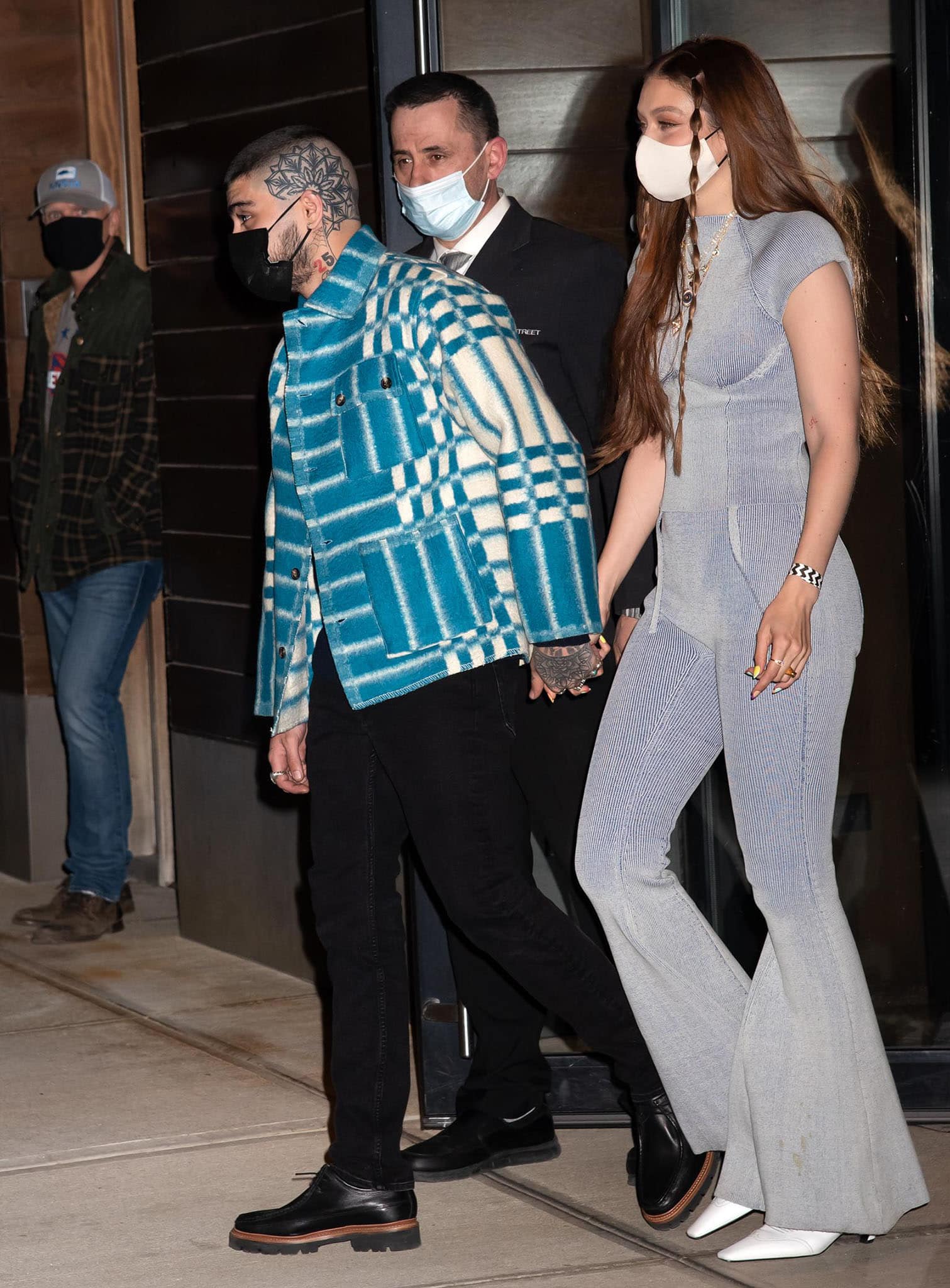 Zayn Malik holds hands with Gigi Hadid in a plaid shirt with black pants and oxford shoes