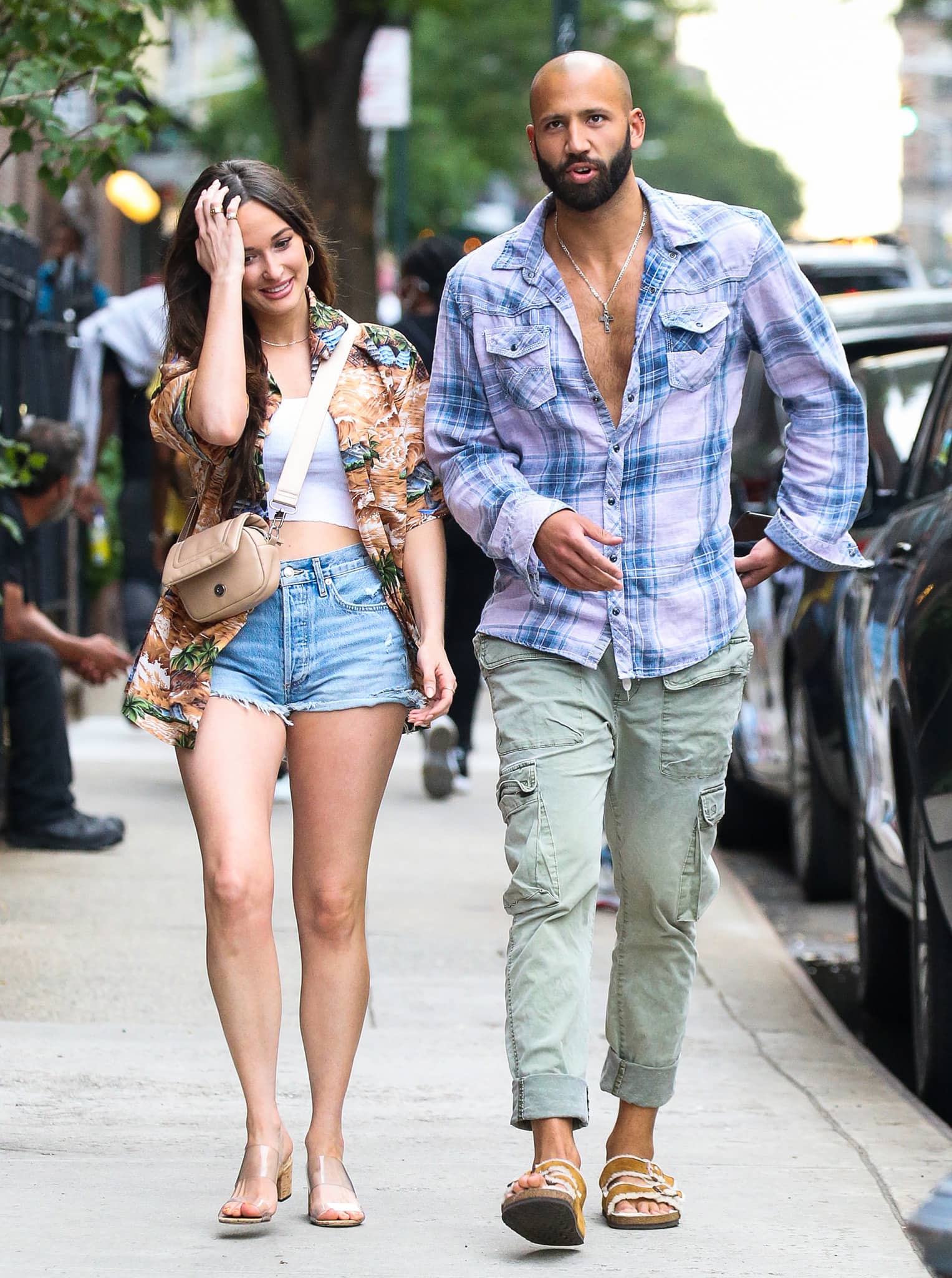 Cole Schafer matches Kacey's summer look with an unbuttoned plaid shirt, green cargo pants, and Birkenstock sandals