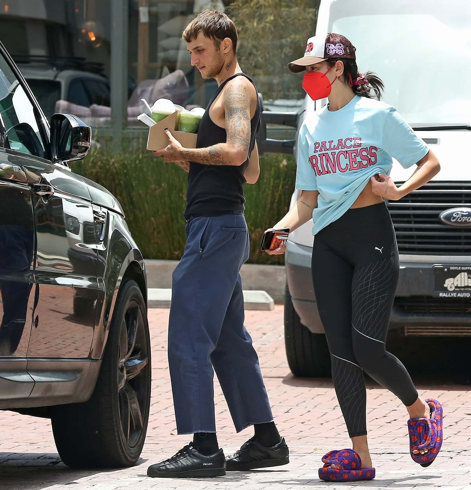 Anwar Hadid shows off his tattoos in a black tank top paired with loose pants and Prada sneakers