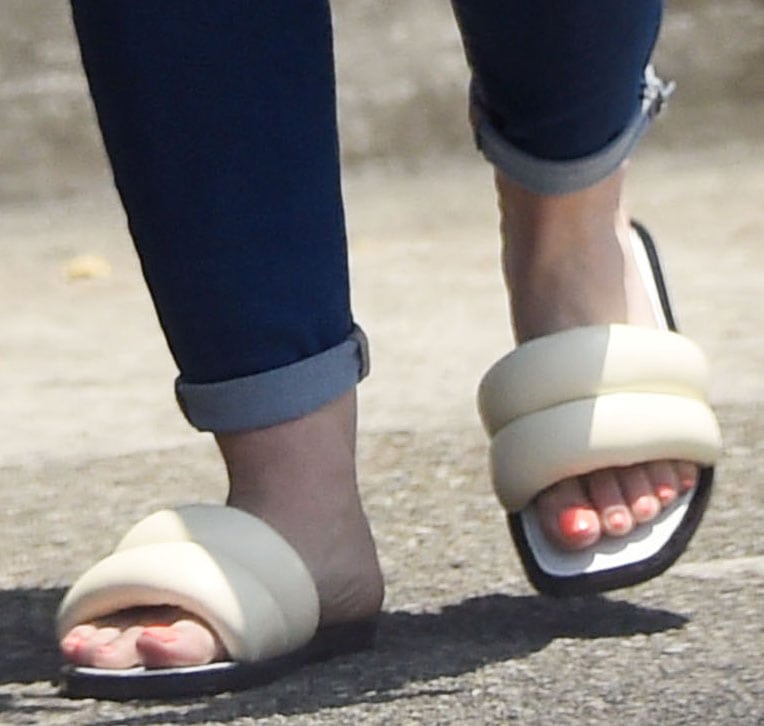 Hilary Duff wears Proenza Schouler Puffy slide sandals, featuring a plush quilted strap and a sleek black sole, paired with a fresh coral-toned pedicure for a chic and comfortable off-duty look