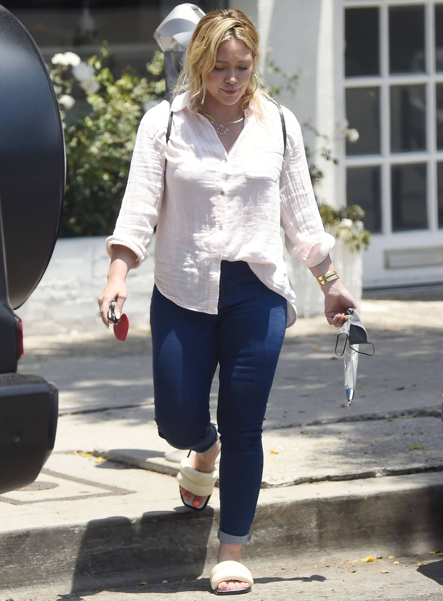 Hilary Duff's casual outfit includes a white long-sleeved shirt and a pair of skinny blue jeans