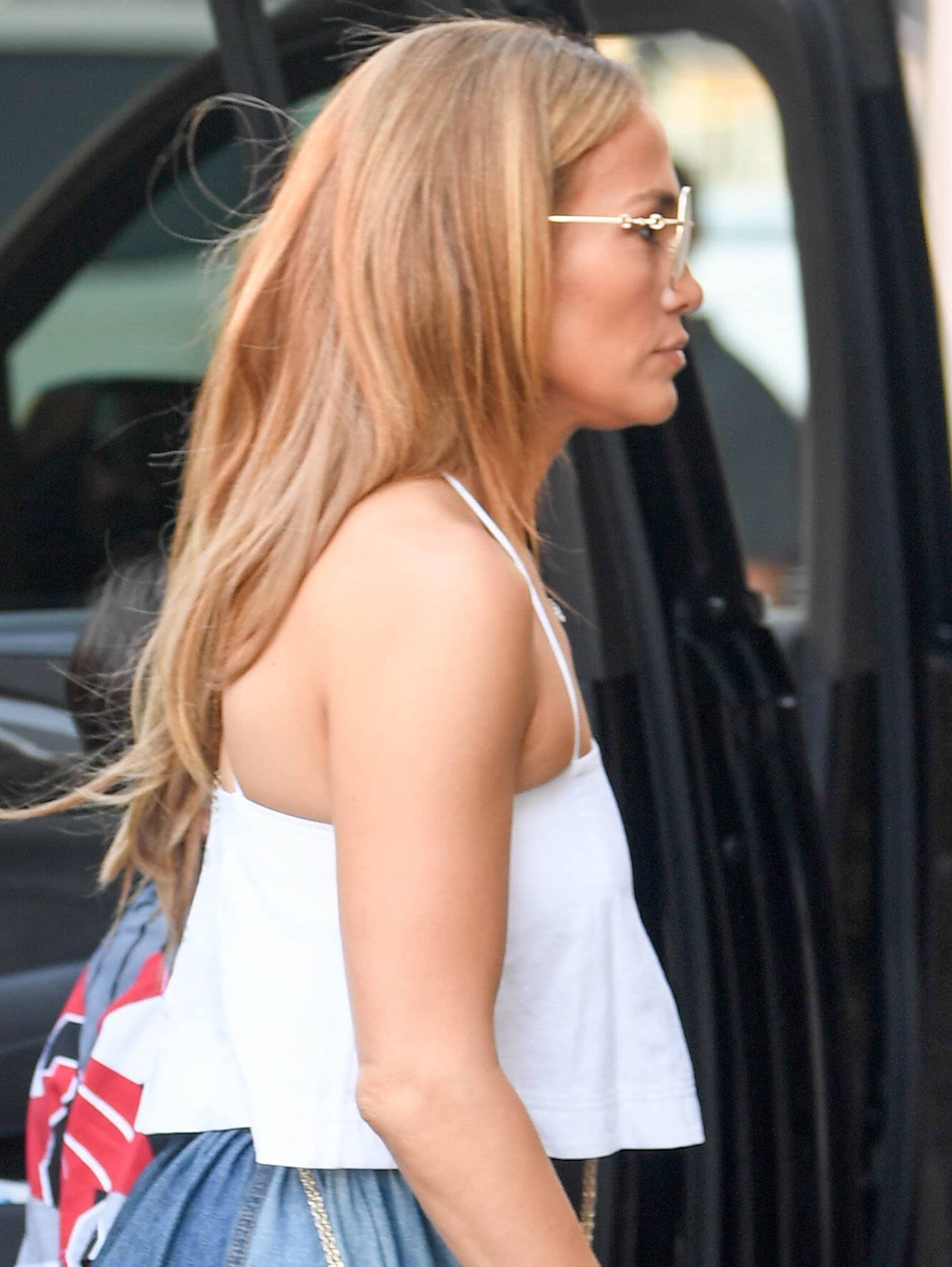 Jennifer Lopez styles her caramel hair down in loose waves and wears neutral makeup with Gucci square sunglasses