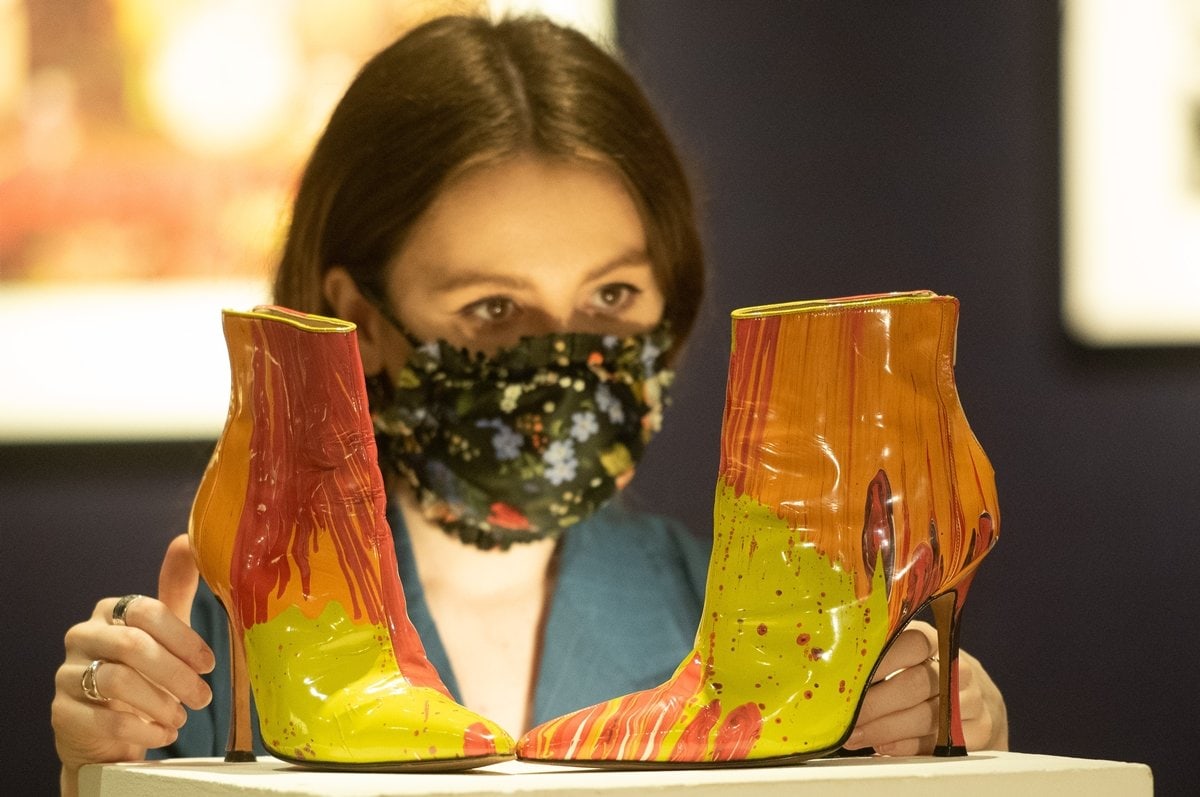 A gallery staff member poses with Damien Hirst X Manolo Blahnik Spin boots