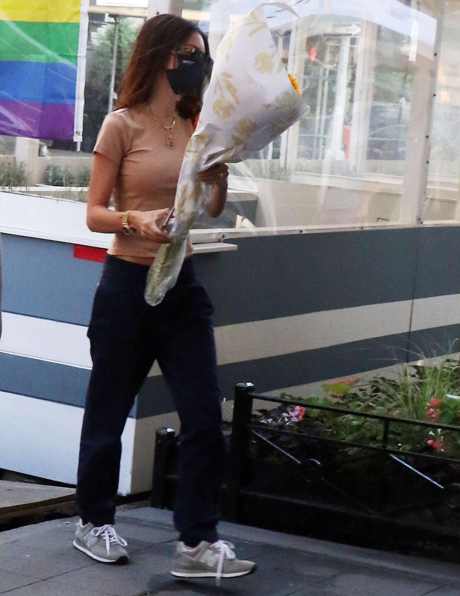 Emily Ratajkowski picking up a bouquet of flowers in Belen nude tee and navy pants in New York City on June 29, 2021