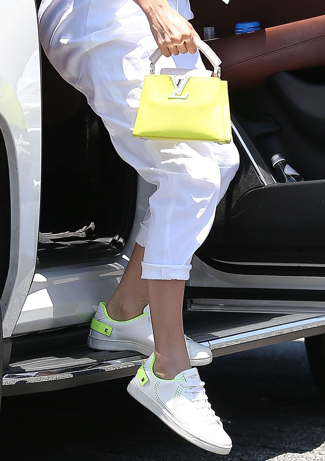 Jennifer Lopez coordinates her yellow Louis Vuitton Capucines Mini bag with her Valentino Backnet Vlogo sneakers