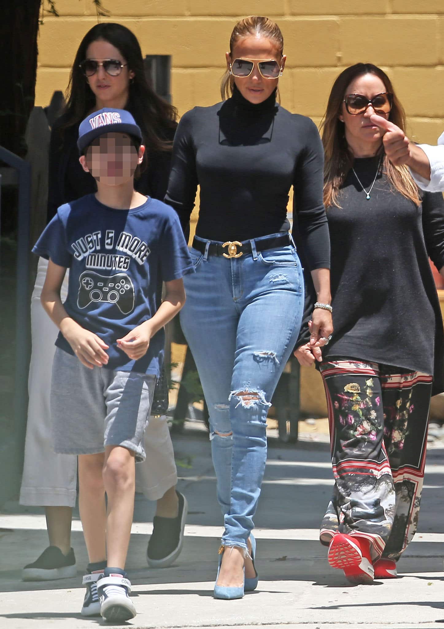 Jennifer Lopez tours a school in Santa Monica with her son, Max, on July 10, 2021, looking chic in a black turtleneck, ripped jeans, a Chanel belt, and blue suede heels