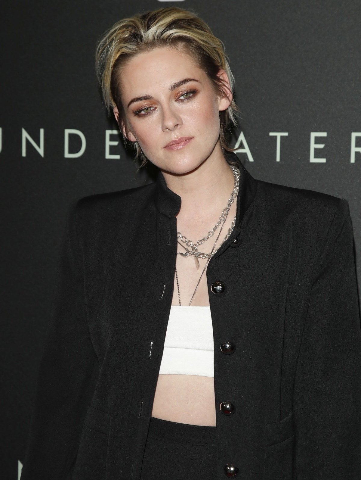 Kristen Stewart wears a black blazer with layered necklaces and a Naked Wardrobe crop top