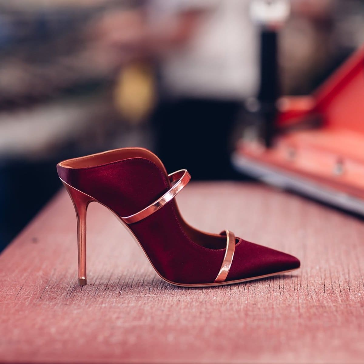 The iconic Maureen mules from London-based label Malone Souliers in lustrous wine-red satin with glossed rose gold leather panels