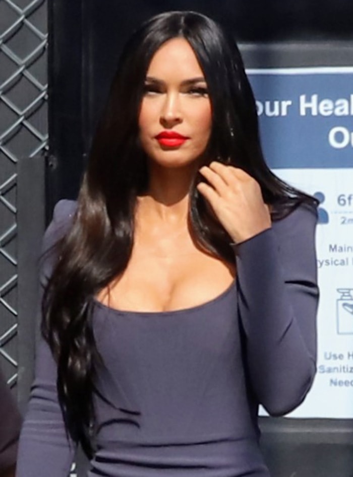 Megan Fox opts for a sultry look with bold red lipstick and hip-length hair in loose curls