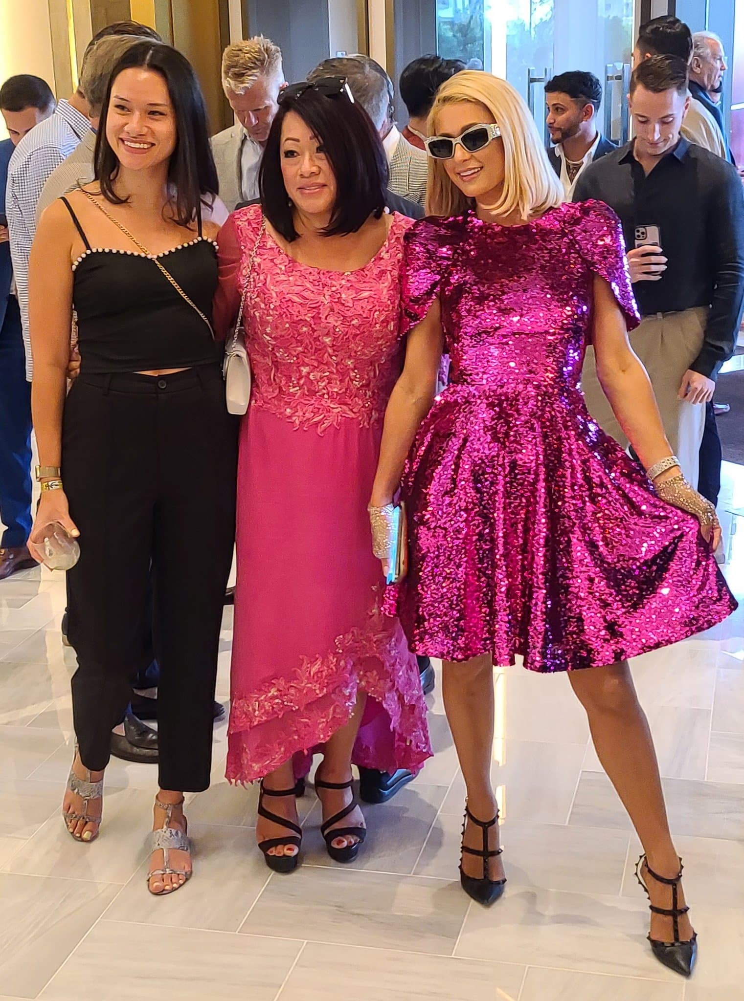 Paris Hilton poses with fans in a fuchsia pink sequined mini dress from Pamella Roland