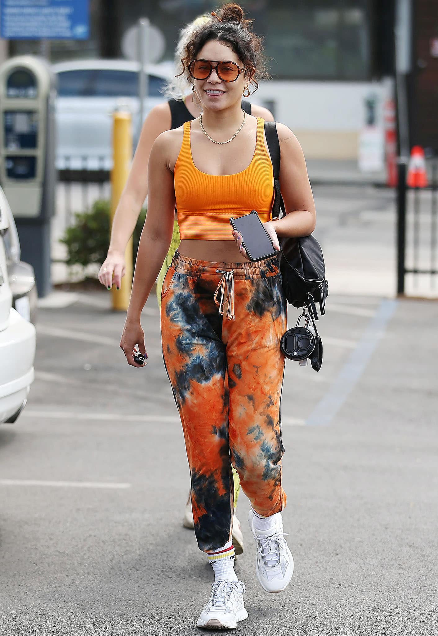 Braless Vanessa Hudgens flashes abs and cleavage in orange sports bra and orange tie-dye joggers