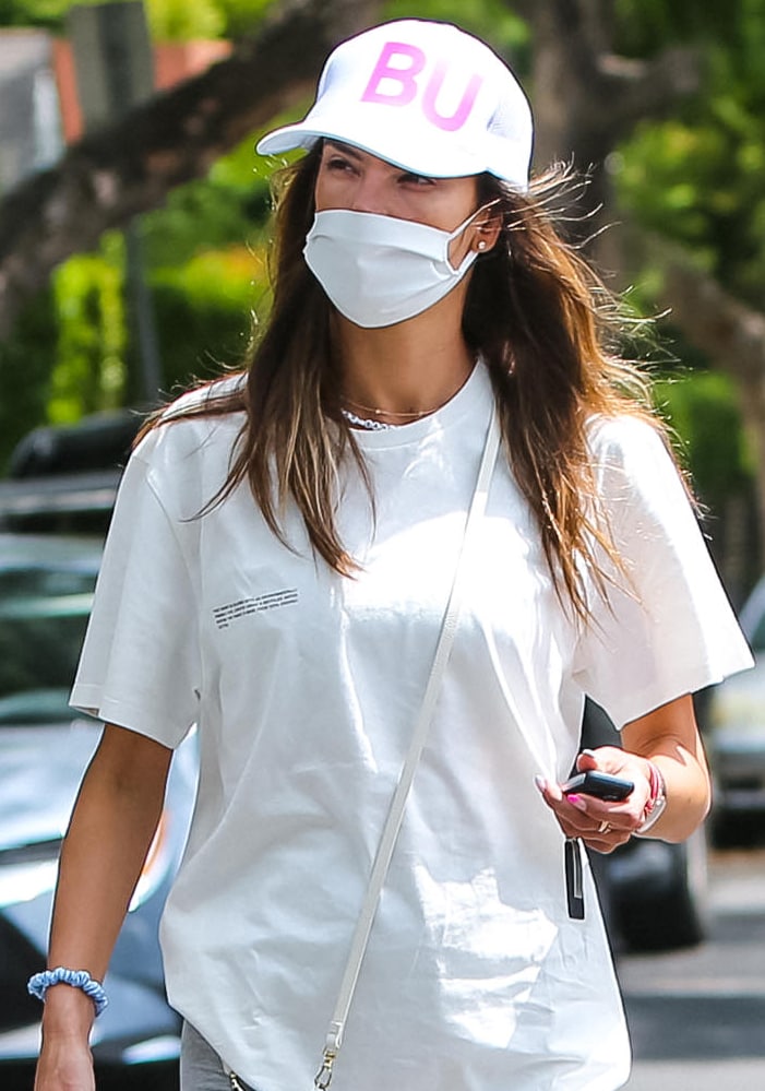 Alessandra Ambrosio keeps a low profile with a trucker cap from Fancy Lids and a white face mask