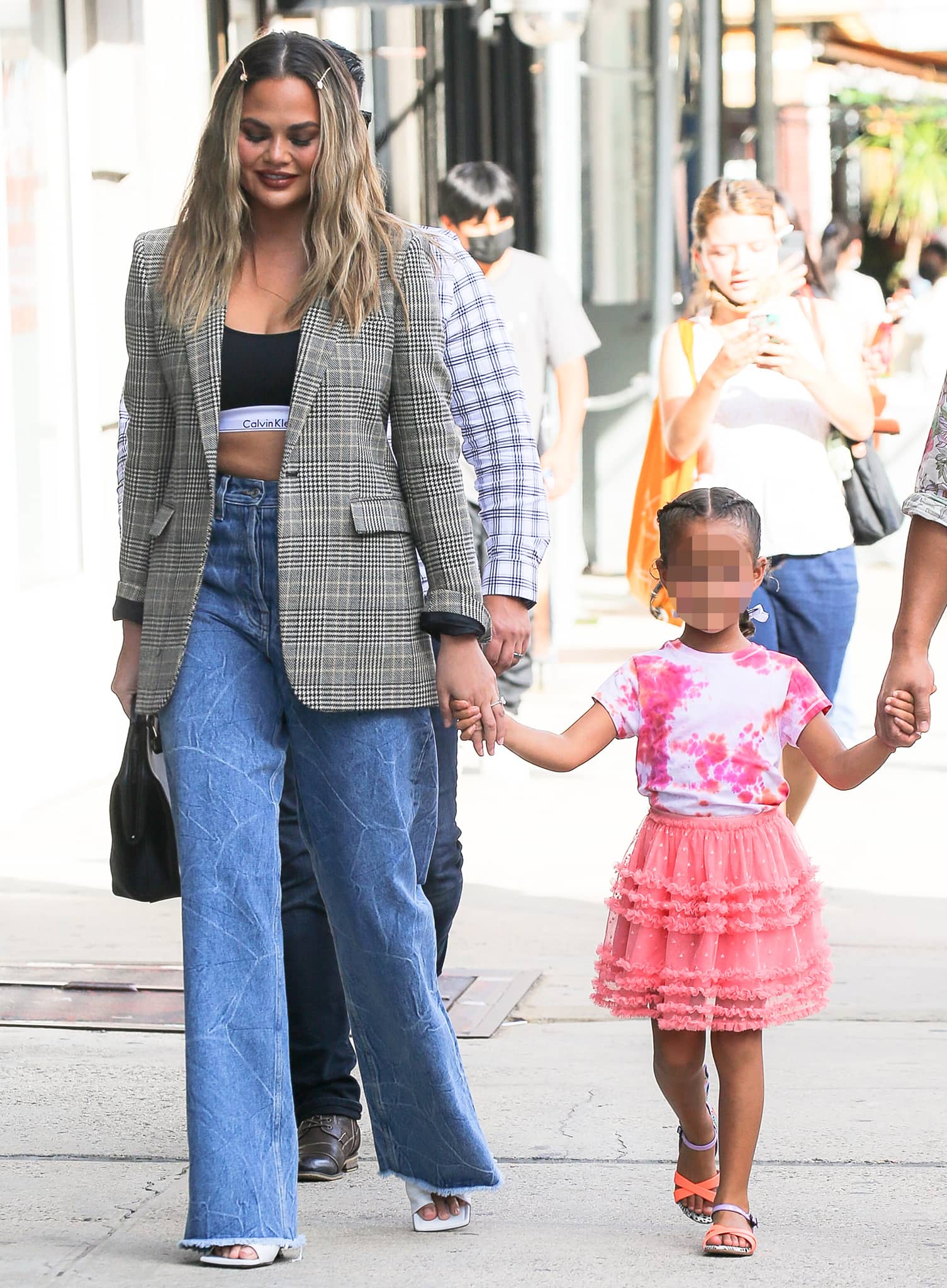 Chrissy Teigen opts for a '90s look in Saint Laurent plaid jacket and Dries Van Noten wide-leg jeans