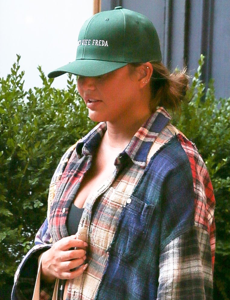 Chrissy Teigen keeps a low profile with a low bun and a green baseball cap