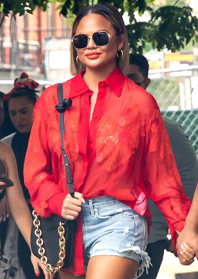 Chrissy Teigen styles her sexy and chic casual look with Bottega Veneta sunglasses, bag, and chunky gold hoops