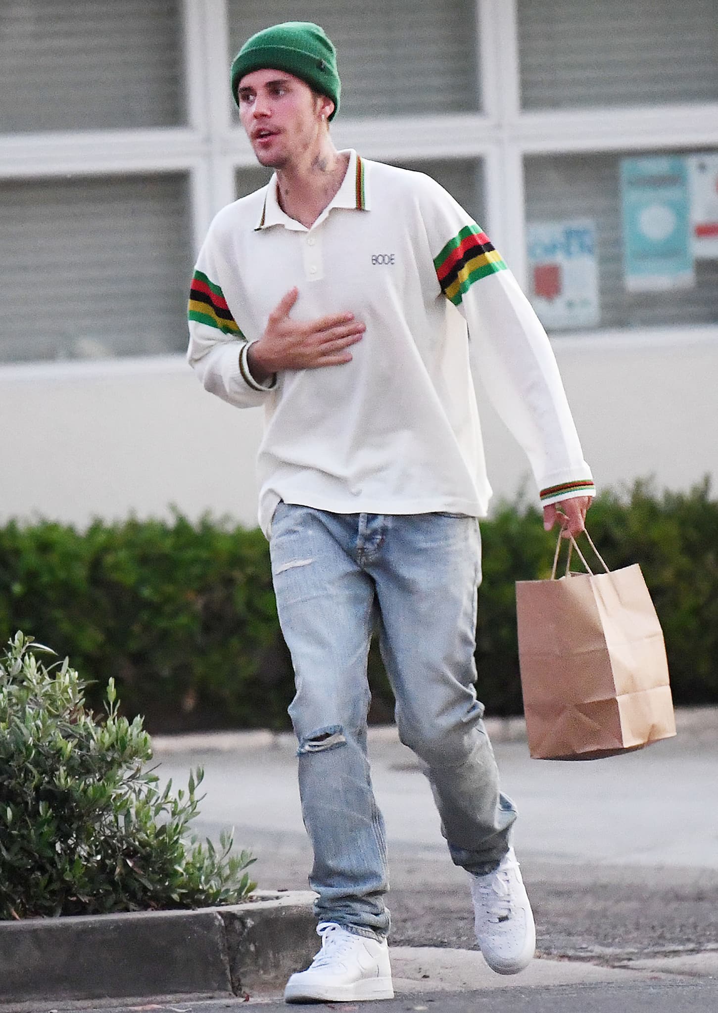 Justin Bieber shows off his cool street style with a long-sleeved polo shirt, light-washed jeans, green beanie, and Nike shoes