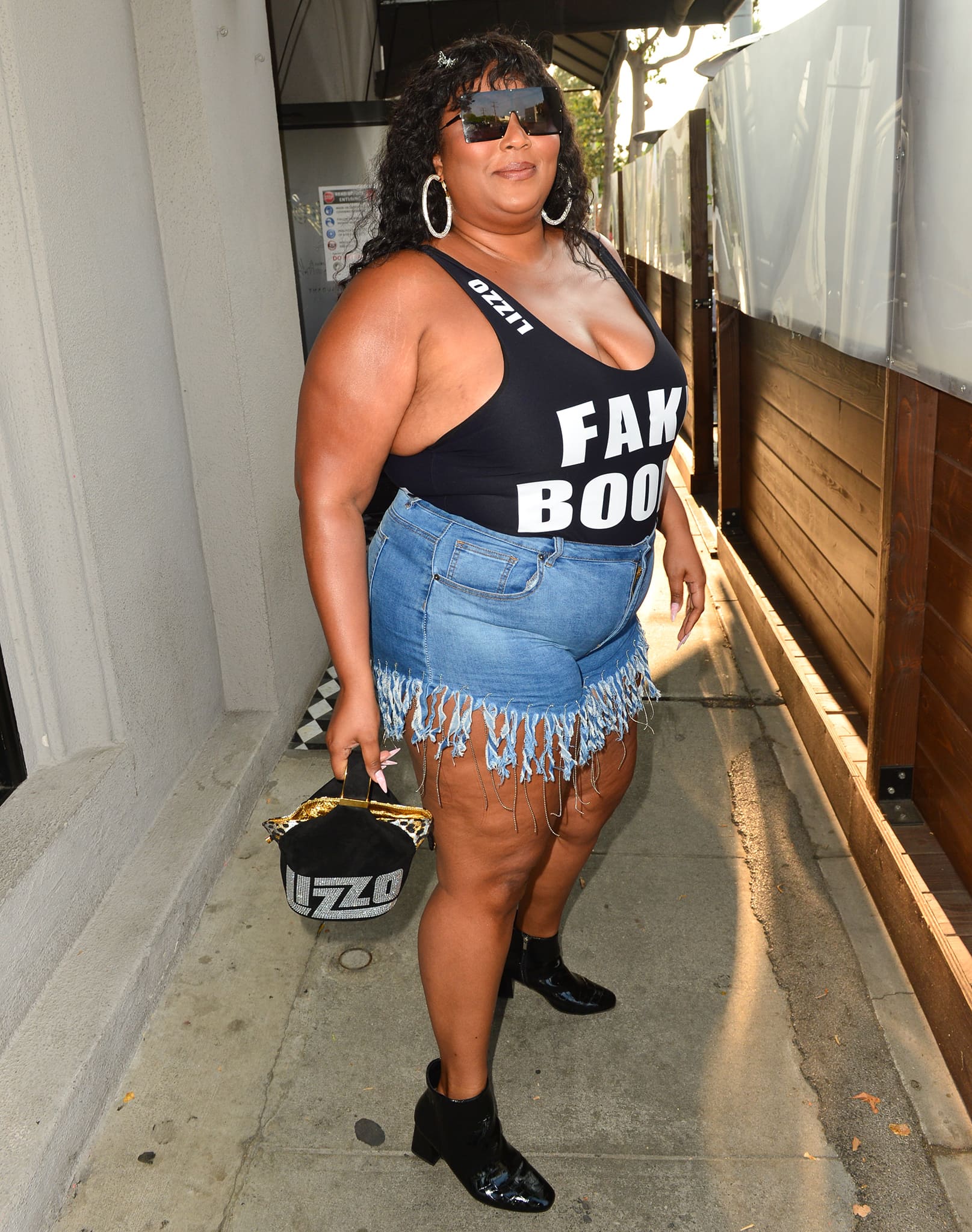 Lizzo confidently shows off her body in a custom Fake Boobs leotard with frayed Daisy Dukes