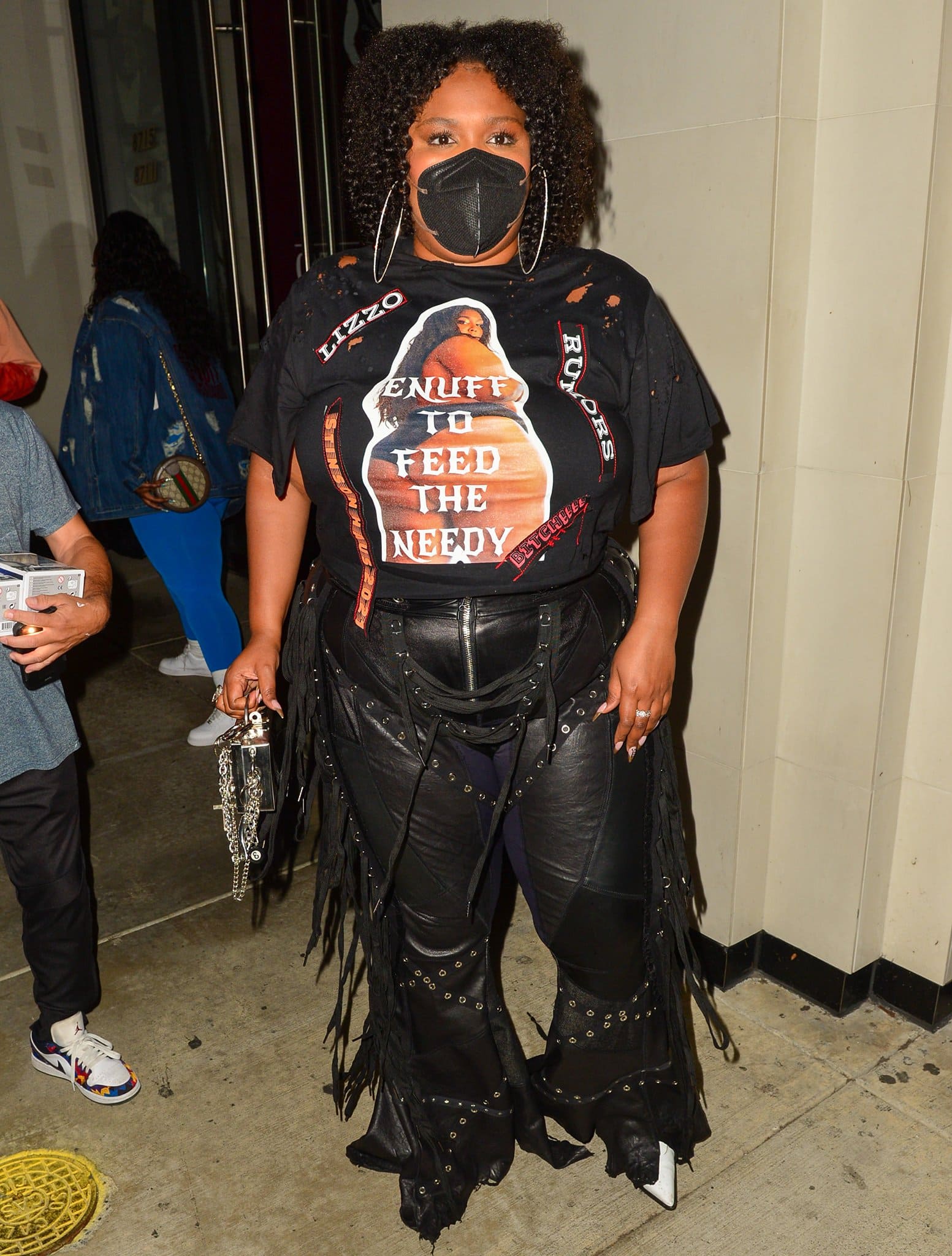 Lizzo wears a pair of fringed leather pants with a black tee printed with her bikini photo on front