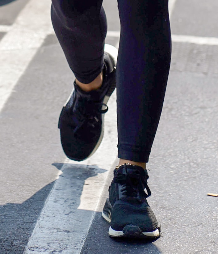 Lucy Hale completes her workout outfit with black Adidas NMD R1 sneakers, featuring a breathable knit upper, signature midsole plugs, and cushioned Boost soles for all-day comfort