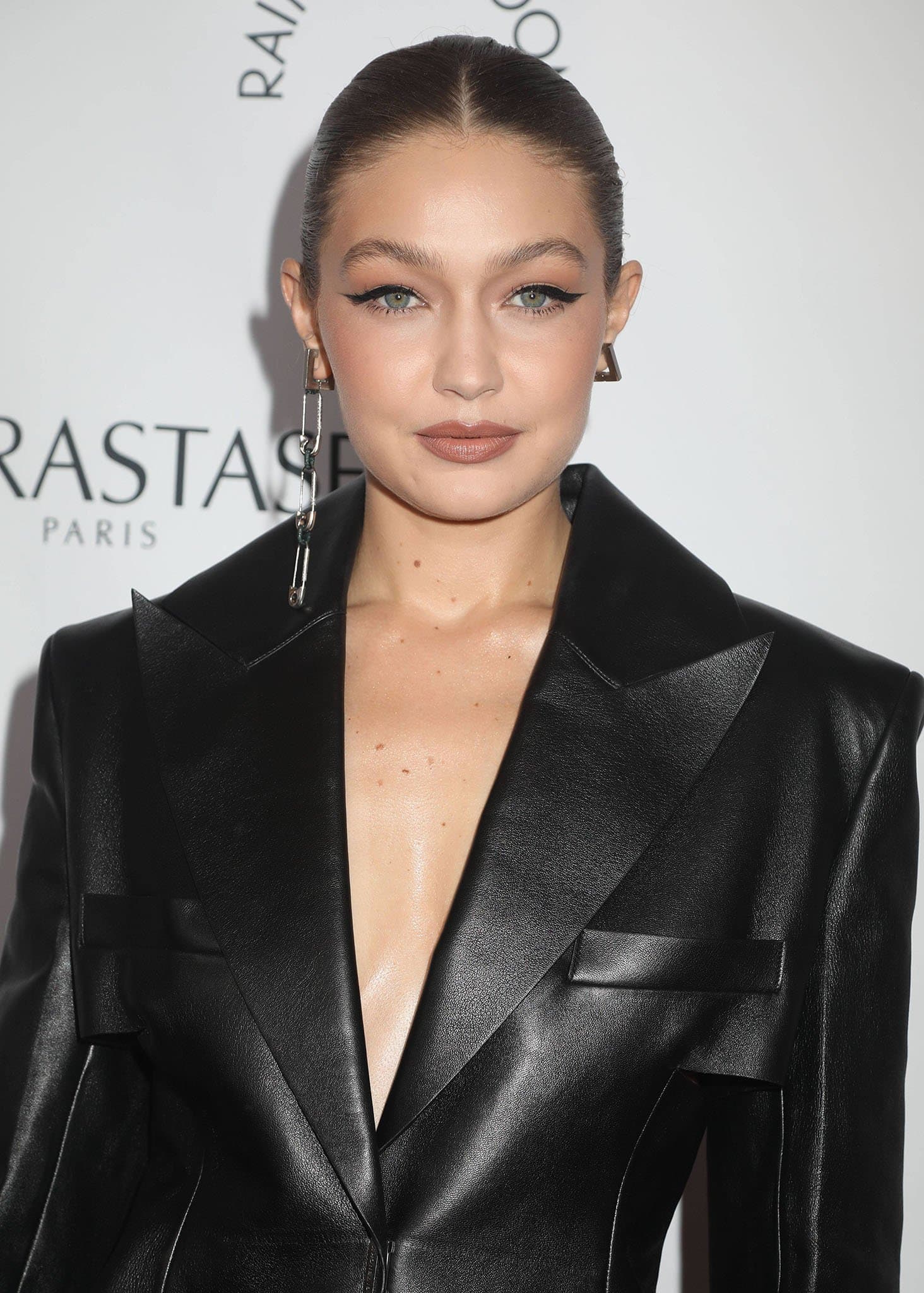 Gigi Hadid styles her hair in a slick braided ponytail and wears winged eyeliner and mauve lipstick