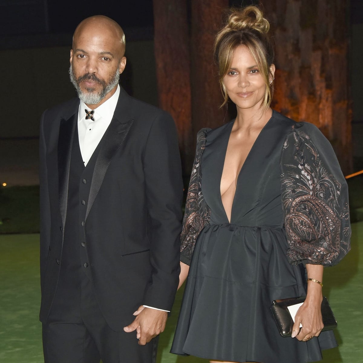 Halle Berry stuns in a plunging black mini dress with puffed sleeves, complemented by her sleek updo, as she attends an event with her partner, Van Hunt