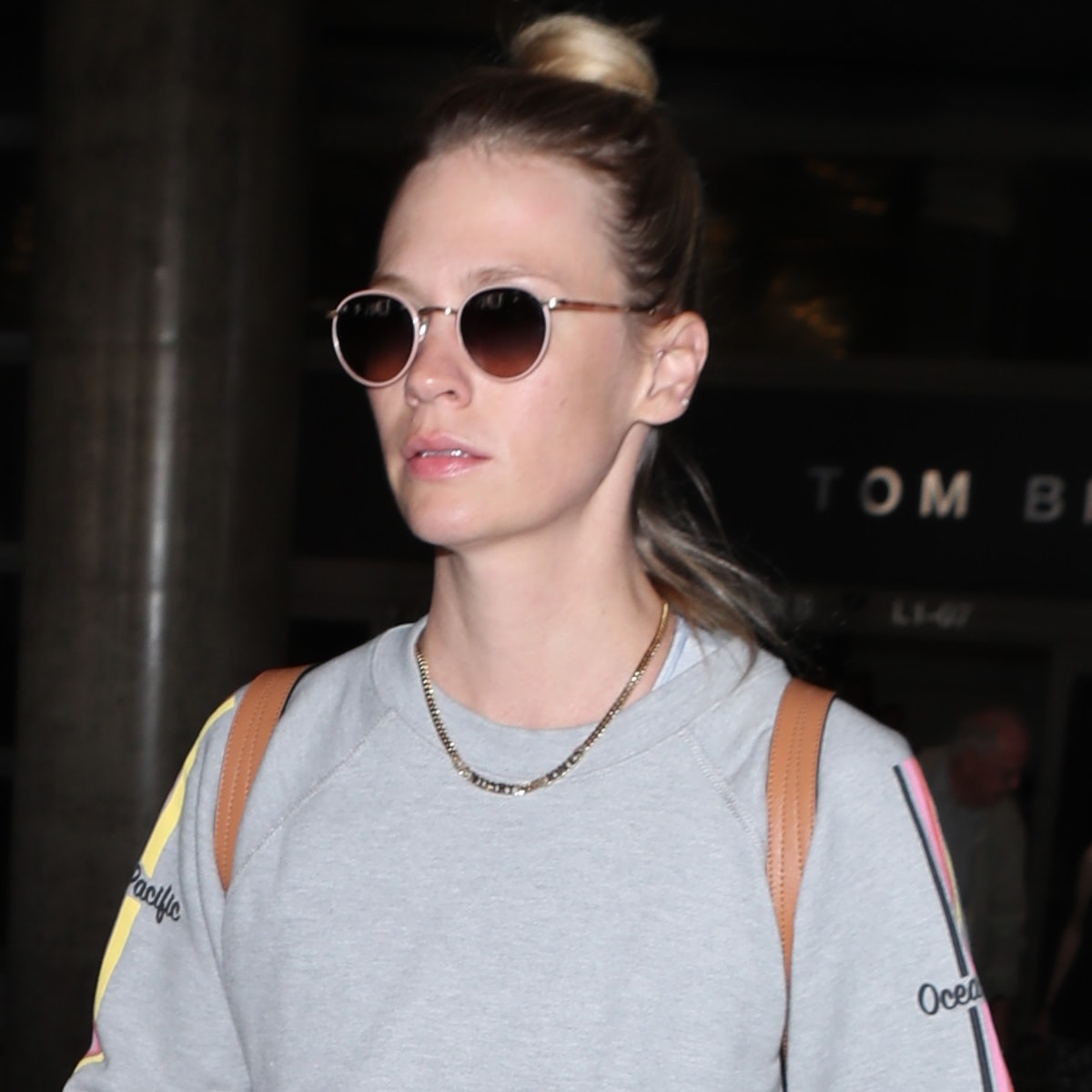 January Jones keeps it casual in a sporty sweatshirt and chic round sunglasses while traveling