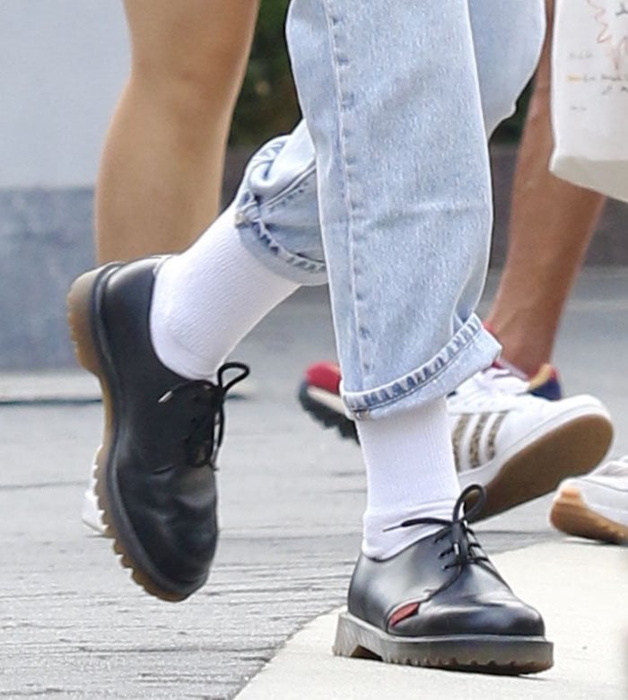 Kristen Stewart pairs her casual chic look with long white socks and Dr. Martens x Royal Mail shoes