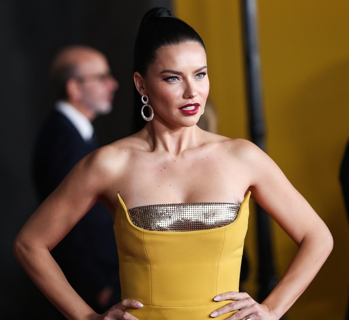 Adriana Lima stuns in a strapless mustard-yellow gown featuring a metallic detail, paired with statement earrings