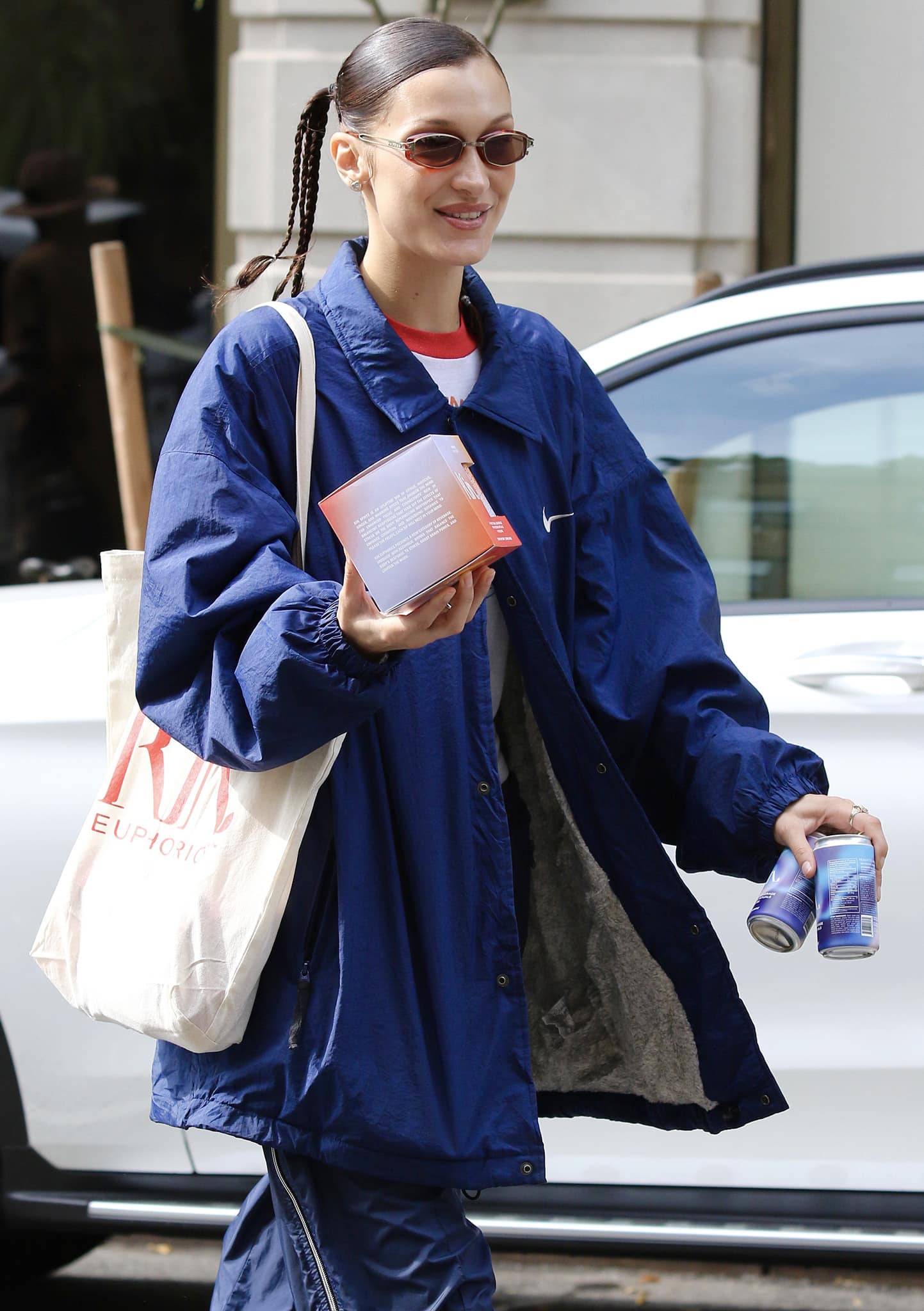 Kin Euphorics co-founder Bella Hadid flashes a smile while carrying a box of her new beverage brand