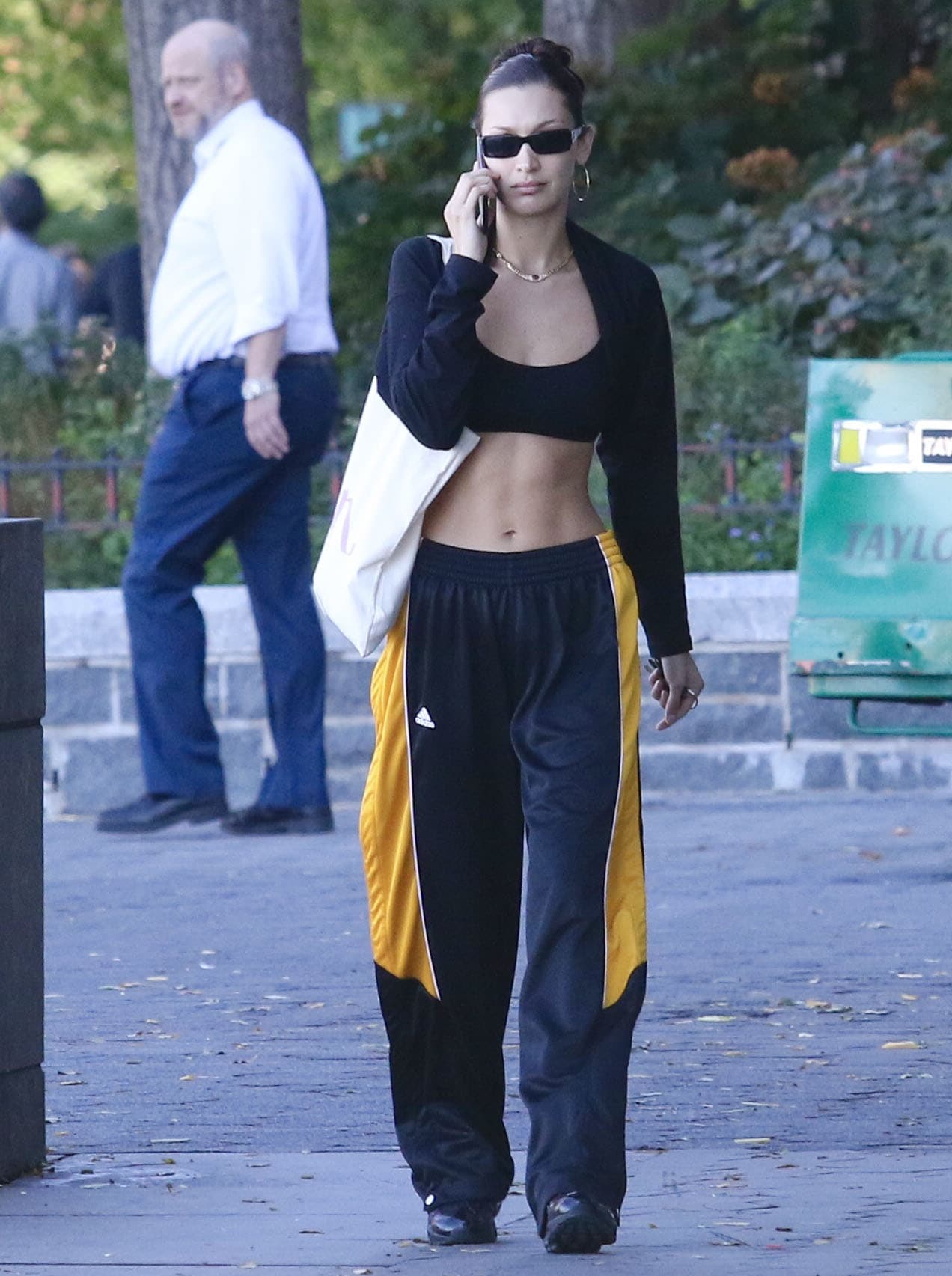 Bella Hadid flashes her toned abs in an Alo Yoga bra top, Adidas track pants, and Alexander McQueen shrug