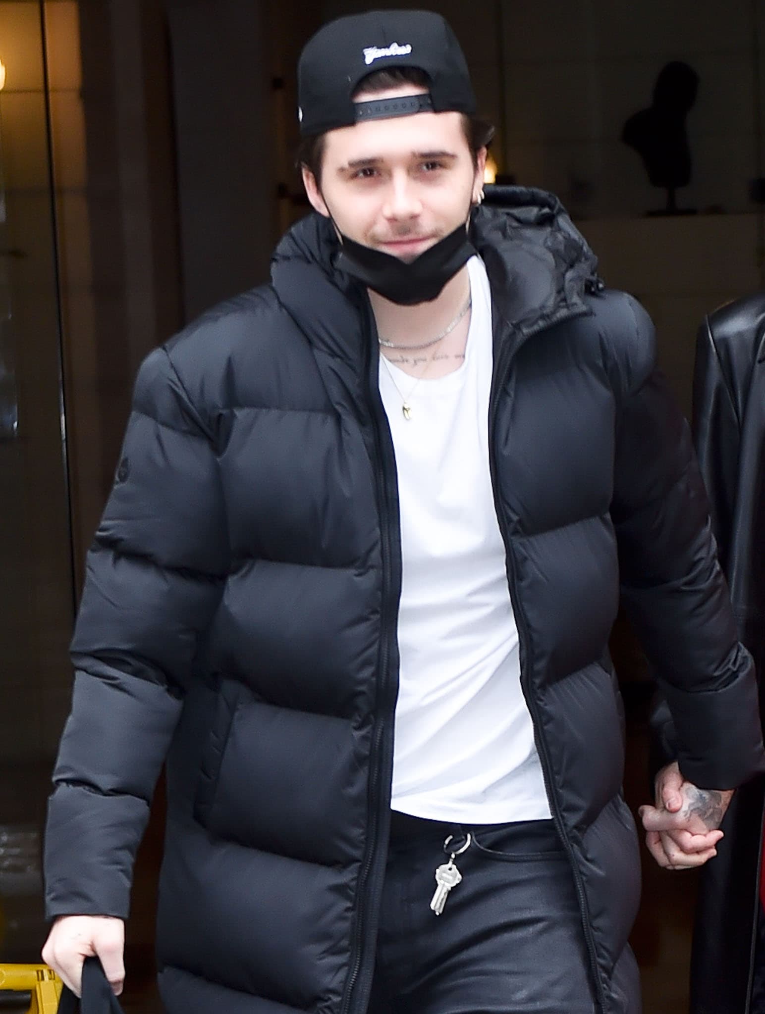 Brooklyn Beckham looks cool in a black Superdry puffy duvet coat with a white tee underneath