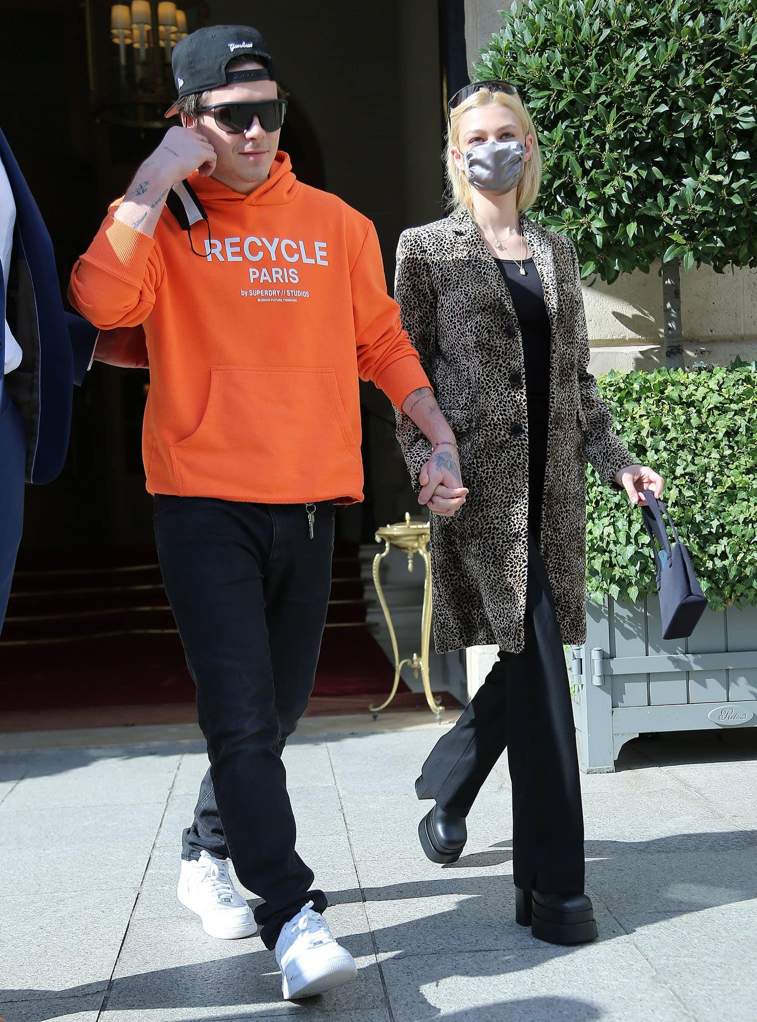 Brooklyn Beckham wears a bold orange Superdry hoodie with black jeans and Nike Air Force 1 shoes