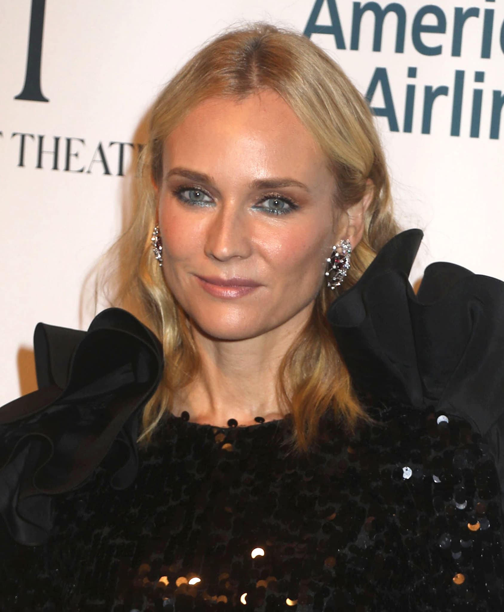 Diane Kruger glams up with bronze eyeshadow, teal bottom eyeliner, nude lipstick, and soft waves hairstyle