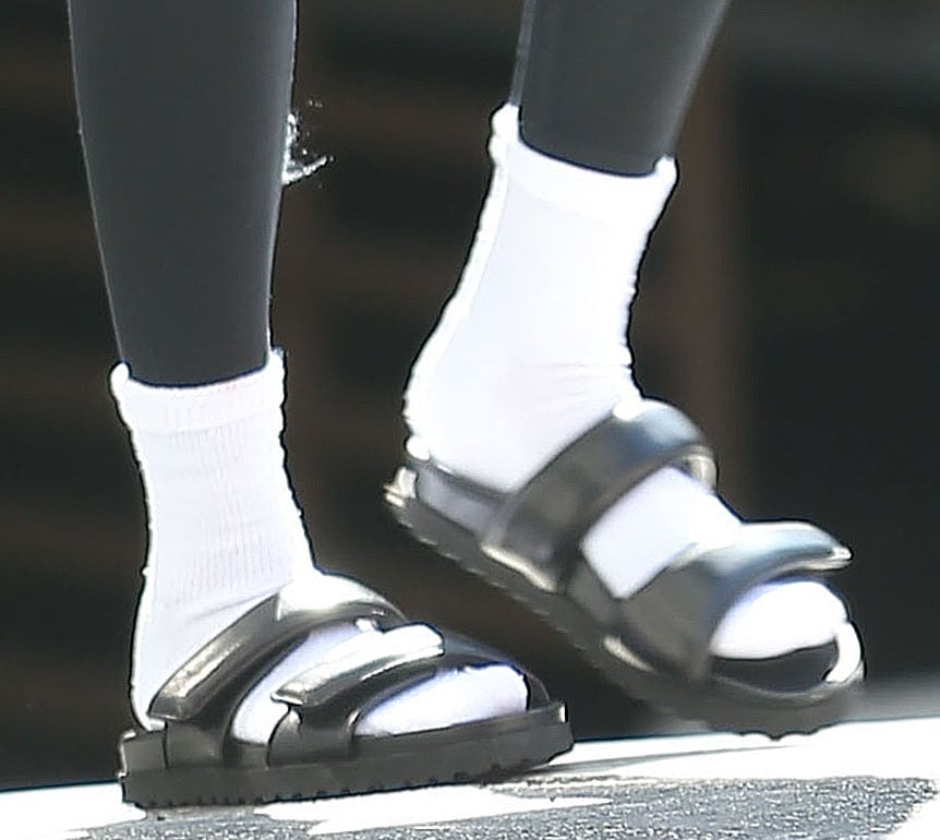 Hailey Bieber slips her feet into a pair of white tube socks and Gia Borghini’s Perni double-strap sandals