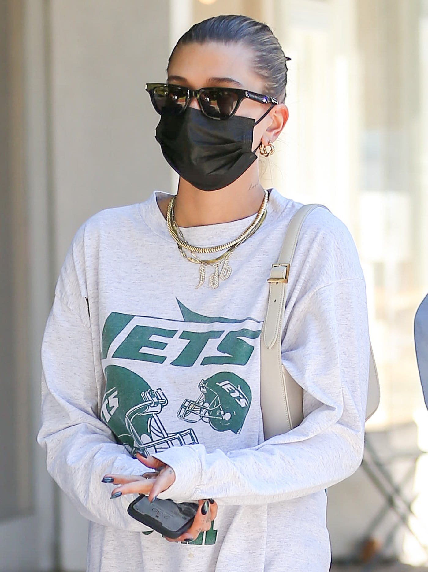 Hailey Bieber wears her signature sleek bun and carries her essentials in a Saint Laurent hobo bag