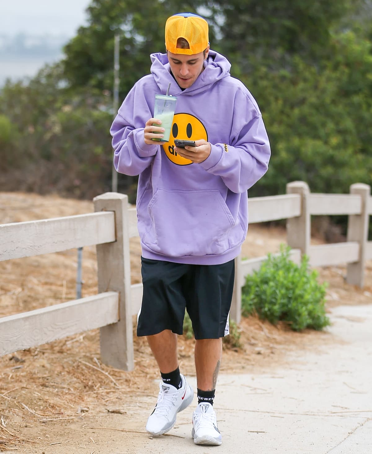 Justin Bieber wears a lavender Drew House mascot hoodie and a trucker hat while hiking in Los Angeles