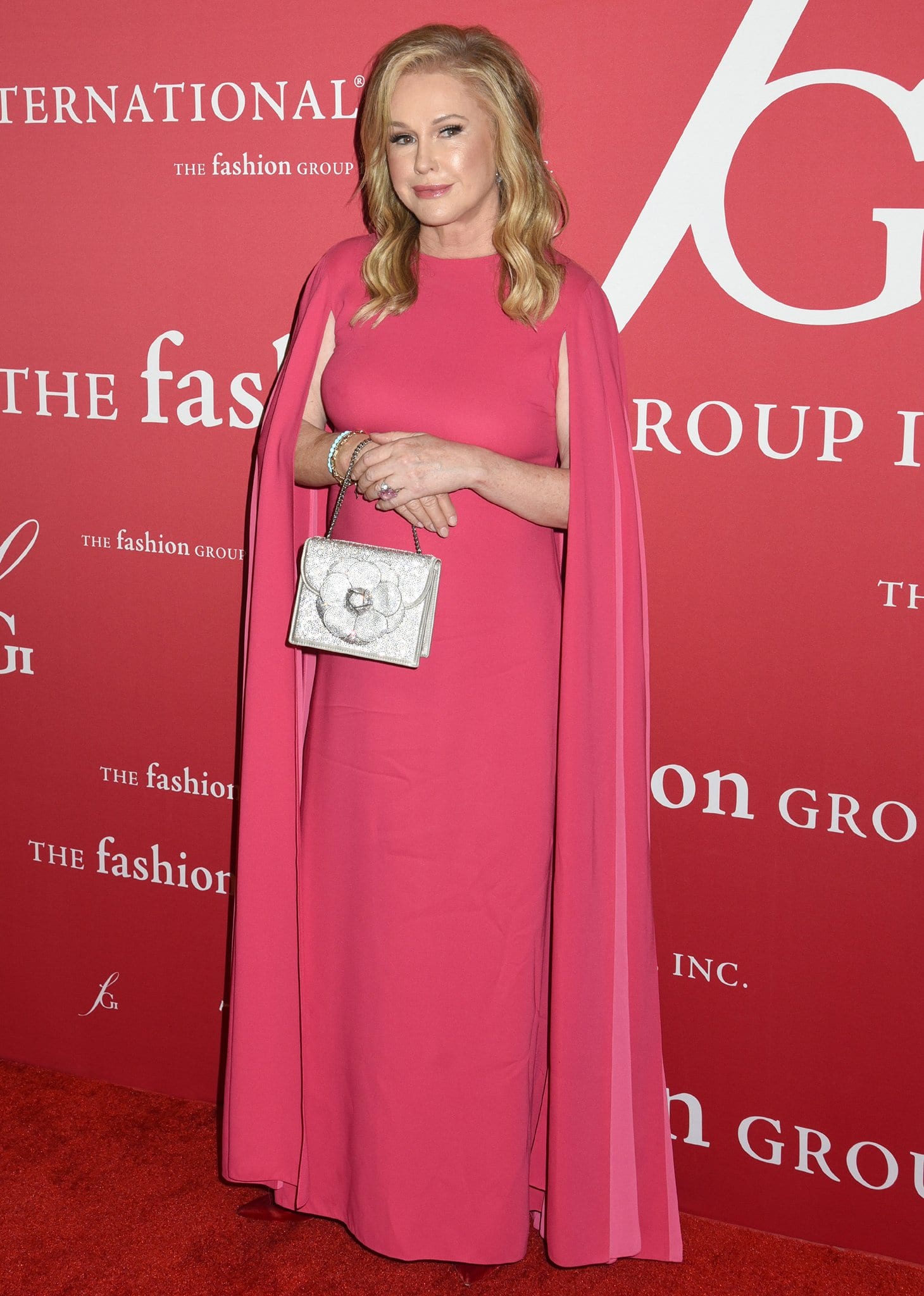Kathy Hilton looks regal in a pink floor-length gown with cape sleeves