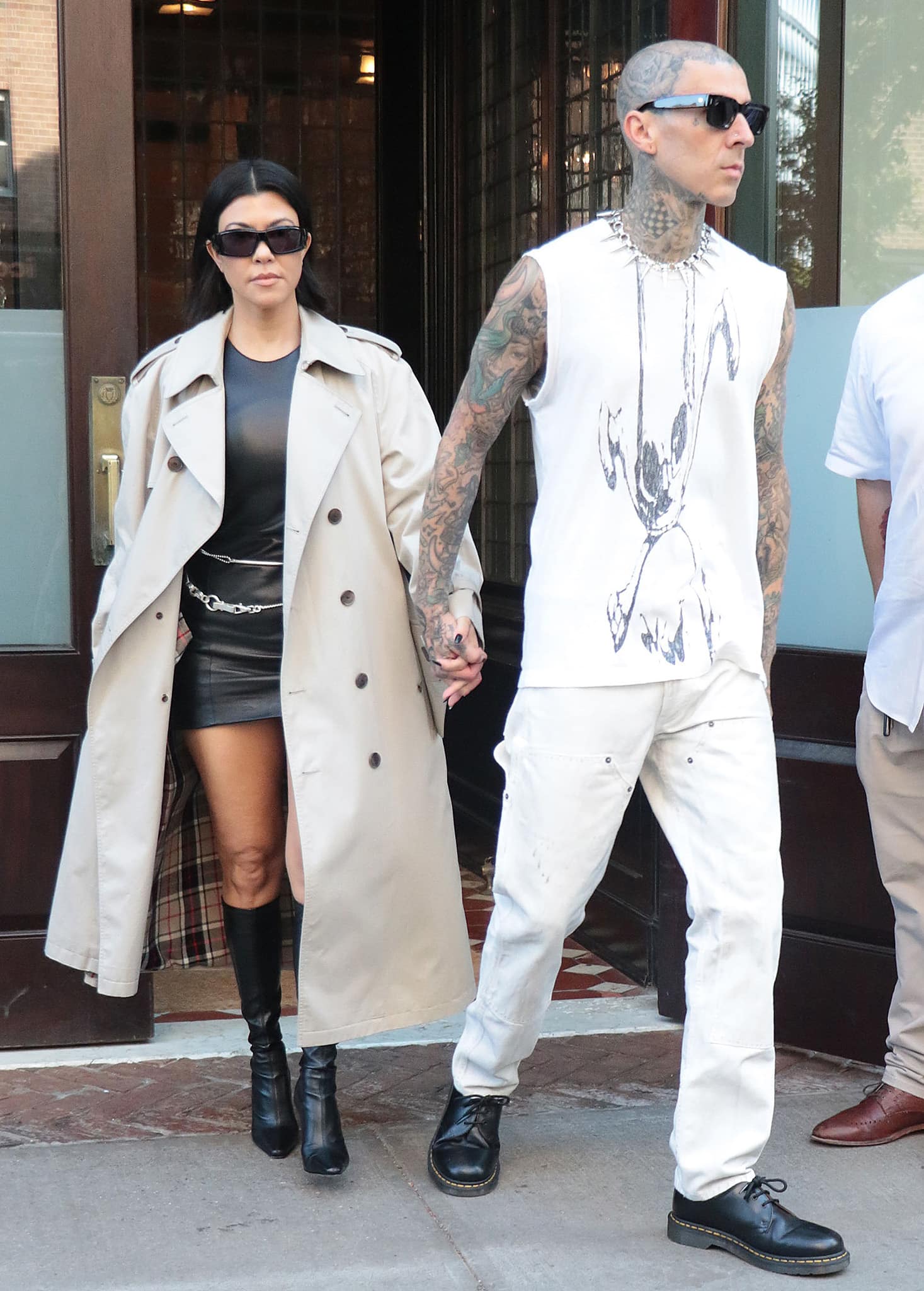 Kourtney Kardashian wears a leather mini dress with a Burberry Westminster Heritage trench coat while Travis opts for a muscle tee with cream-colored jeans