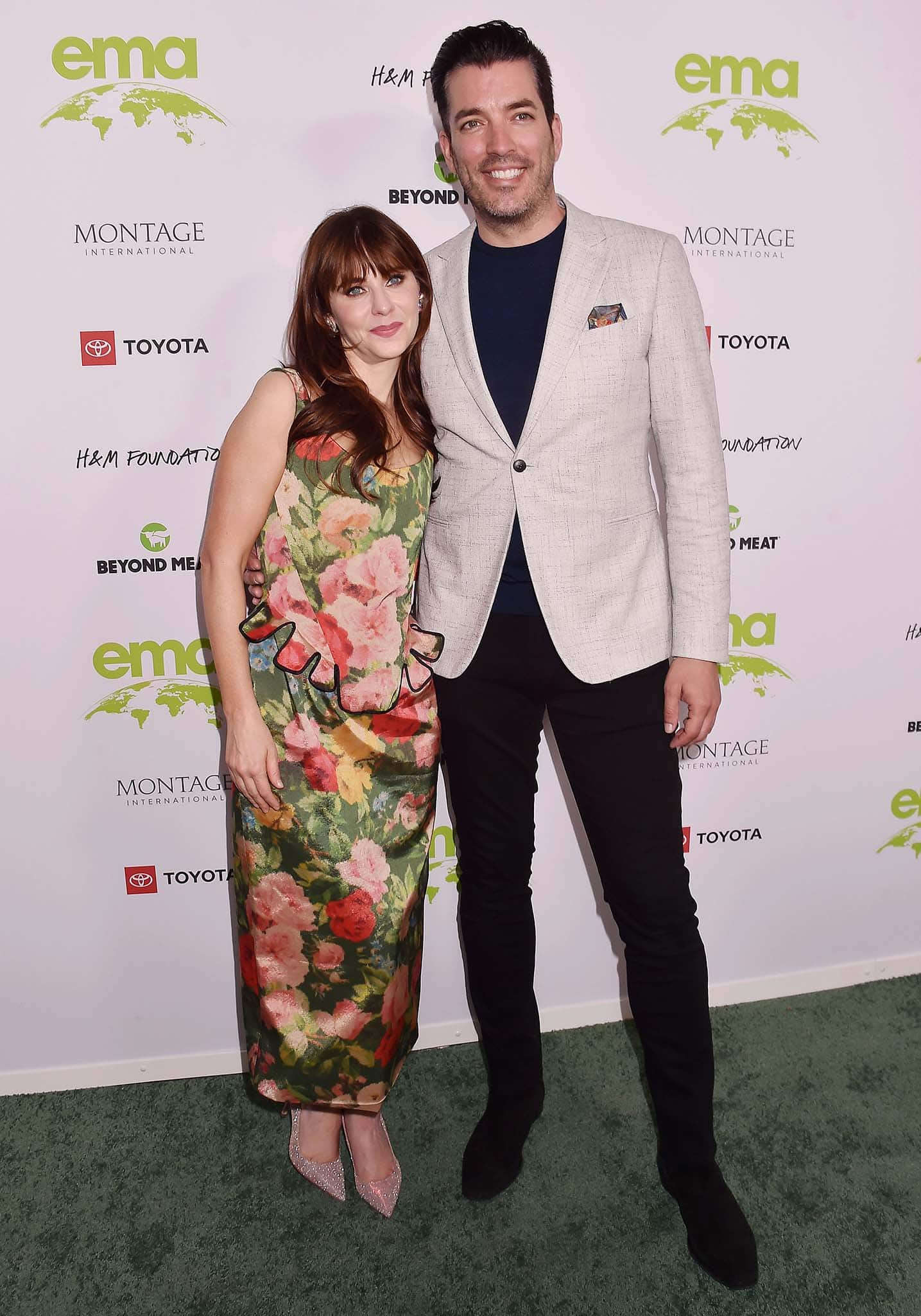 Jonathan Scott wears a black tee, pants, and a beige blazer with a printed pocket square