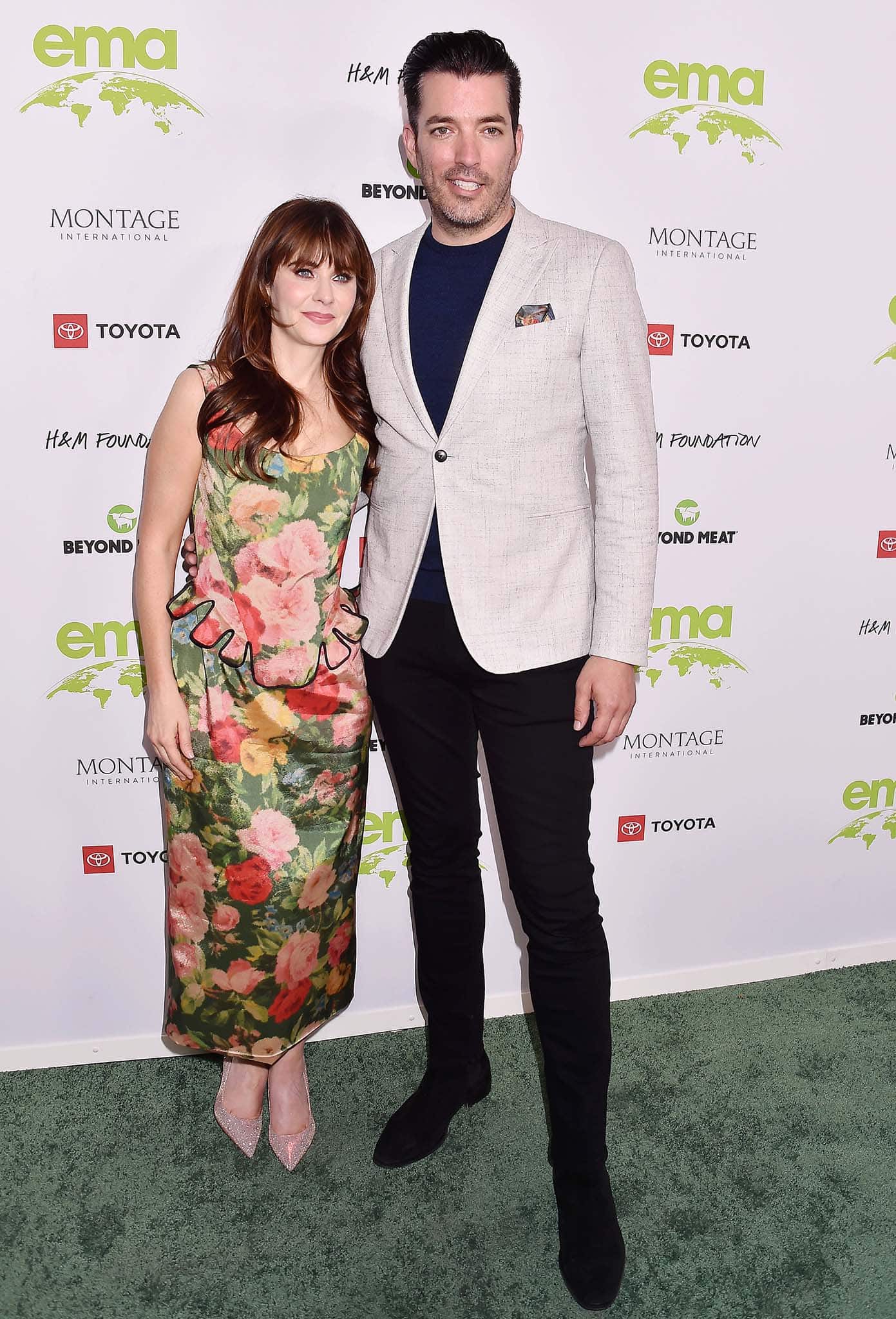 Zooey Deschanel and Jonathan Scott coordinate in complementary ensembles at the Environmental Media Association (EMA) Awards Gala on October 16, 2021—Zooey in a romantic floral Richard Quinn dress and glittering pumps, and Jonathan in a sleek beige blazer over a navy tee and black trousers