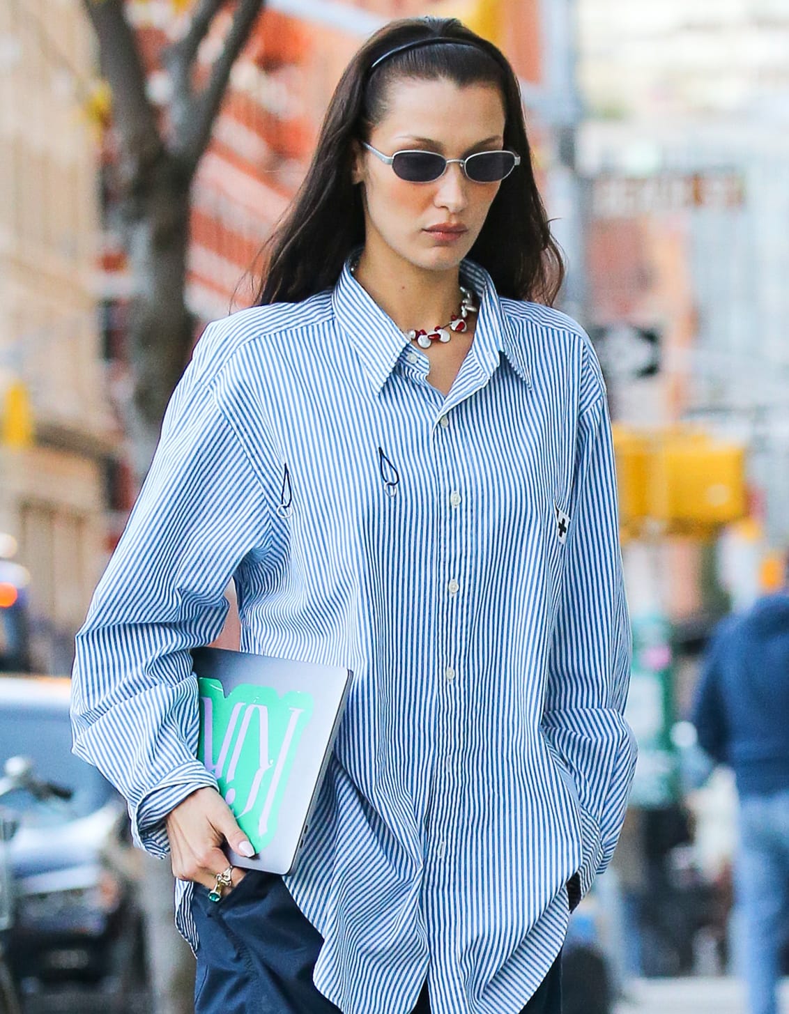 Bella Hadid keeps her long brown hair off her face with a headband and wears peach blush and pink lipstick