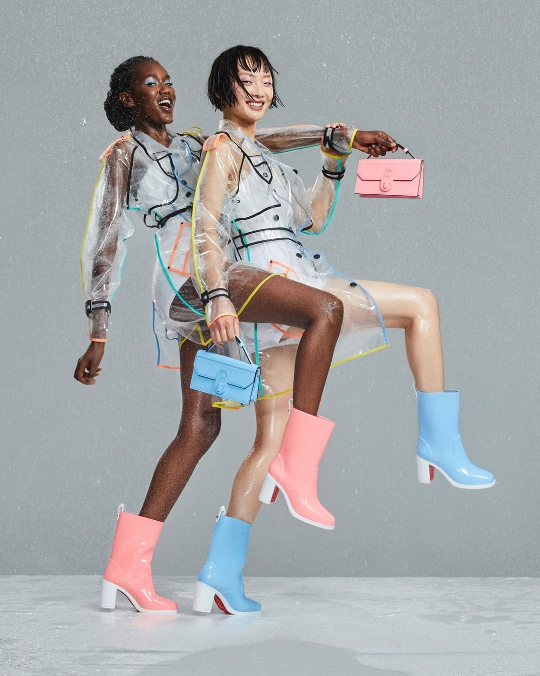 Two models show off their Christian Louboutin’s Loubirain rain boots and matching small Elisa Baguette clutch bags