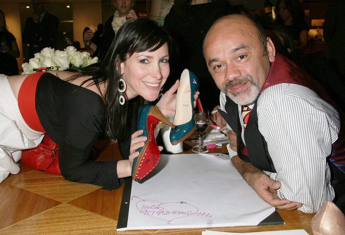 Shoe designer Christian Louboutin signs his famous red sole shoes for fans at Barneys New York