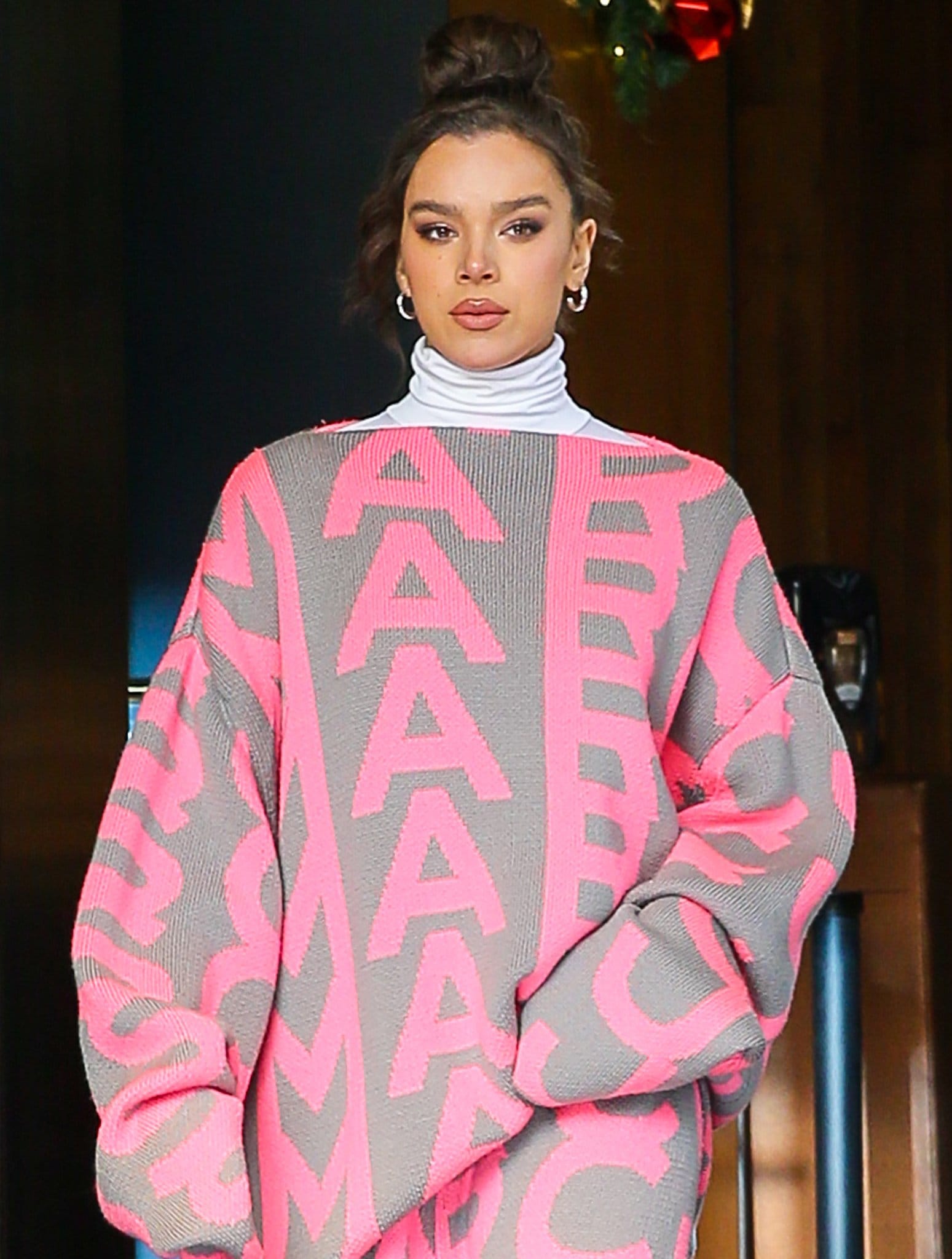 Hailee Steinfeld wears a '90s top knot hairstyle with metallic smokey eyes and pink lips