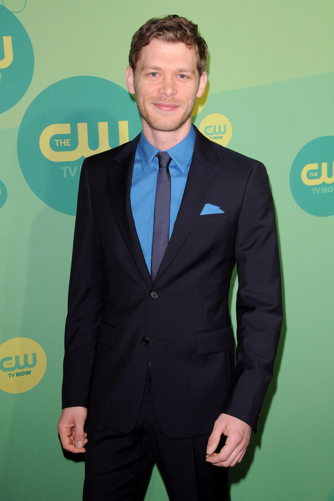 Joseph Morgan attends a CW event, looking sharp in a navy suit paired with a bold blue shirt and matching pocket square