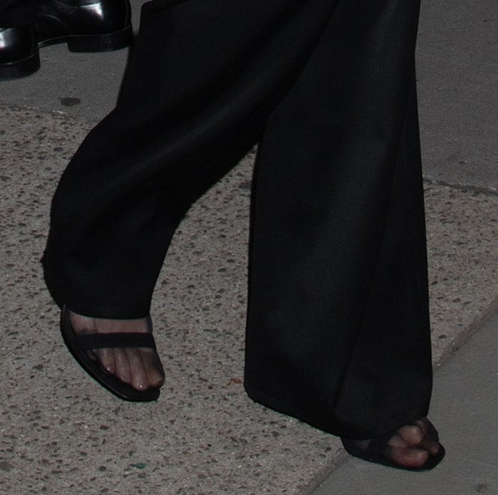 Karlie Kloss completes her chic all-black ensemble with stockings and Manolo Blahnik sandals